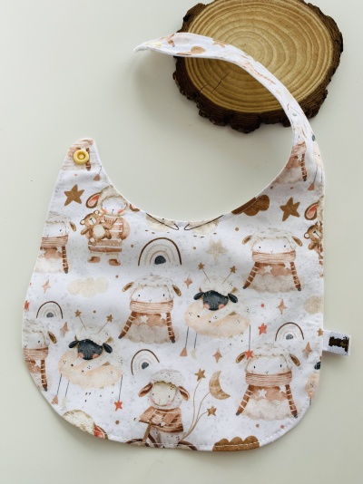 Babeiro branco com padrões de ovelhas e elementos decorativos em tons castanhos e bege