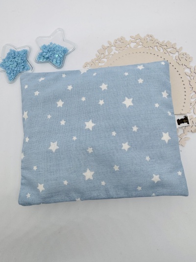 Almofada azul com estrelas brancas ao lado de embalagens em forma de estrela com grânulos azuis