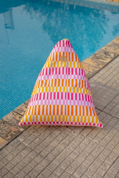Almofada colorida com riscas verticais perto de uma piscina