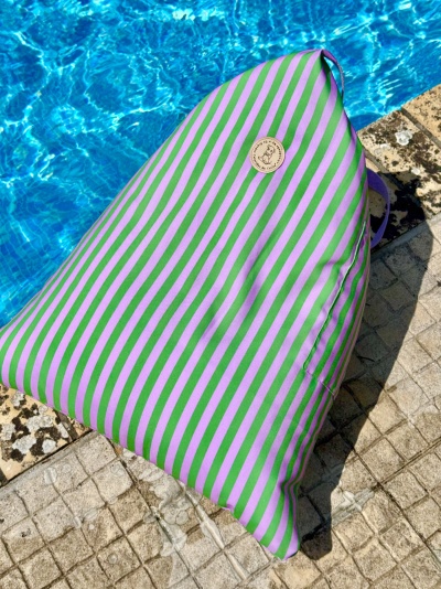 Almofada triangular riscada verde e rosa junto à piscina