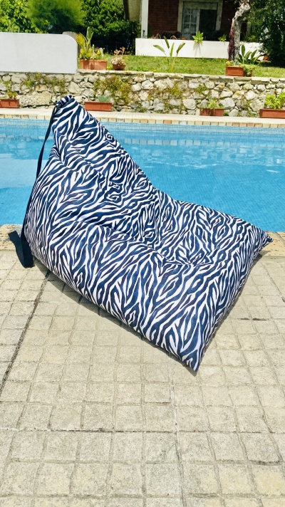 Puff com padrão zebra preto e branco junto a uma piscina ao ar livre