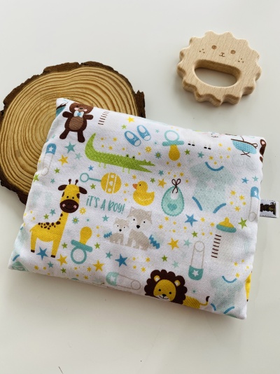 almofada infantil estampada com animais e acessórios de bebé junto a brinquedo de madeira em forma de leão