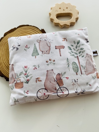 Almofada estampada com ursos e elementos naturais junto a brinquedo de madeira em forma de leão