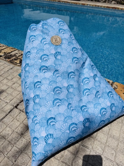 Pufe azul claro com padrão de conchas ao lado de piscina