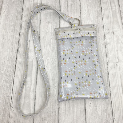 Bolsa transparente pequena com padrão floral e alça comprida sobre fundo de madeira clara