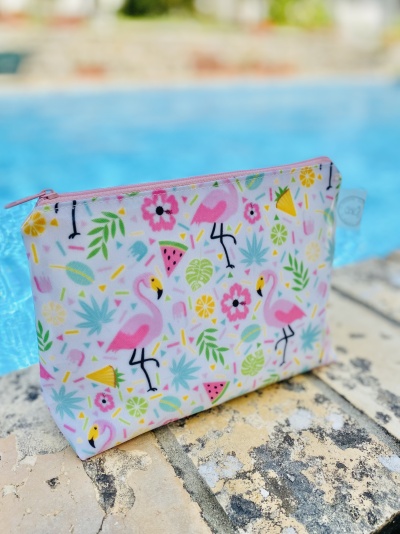 Necessaire com padrão de flamingos e elementos tropicais junto a piscina