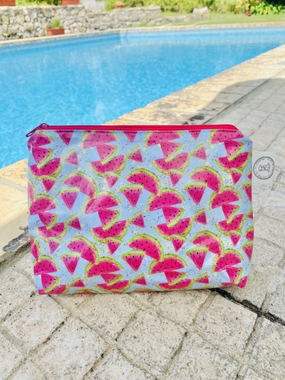 Bolsa colorida com padrão de melancias ao lado de piscina