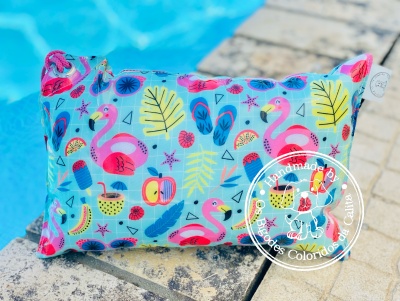 Almofada azul com flamingos e elementos tropicais junto à piscina