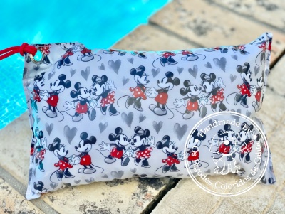 Almofada retangular com padrão de Mickey em fundo cinza azul claro junto a piscina