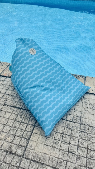 Pufe inflável azul com padrão de ondas junto à piscina
