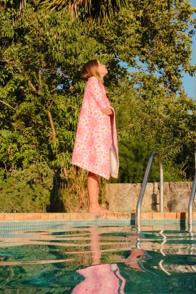 Toalha de praia rosa com flores perto de piscina ao ar livre