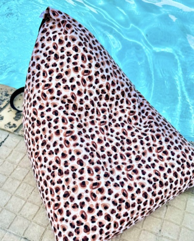 Pufe triangular com padrão de estampa animal junto a uma piscina