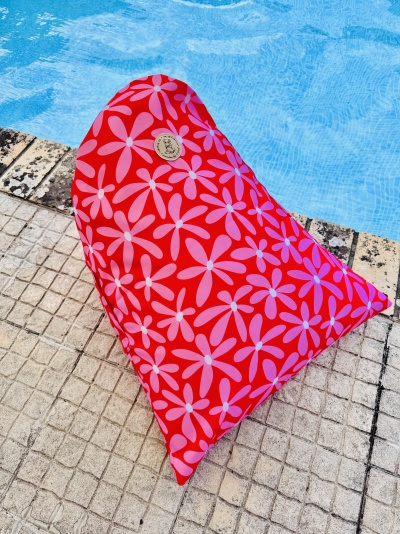 Almofada vermelha com flores rosa junto à piscina