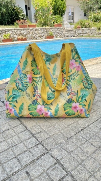 Saco de praia amarelo com padrão de folhas e flores junto à piscina