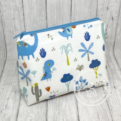 Necessaire branca com padrão colorido de dinossauros e plantas, fecho azul