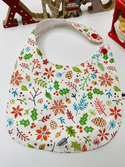 Babete de bebé com padrão floral e folhas coloridas em fundo branco