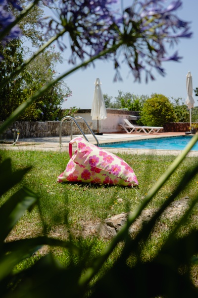Almofada triangular floral junto a uma piscina e espreguiçadeiras exteriores