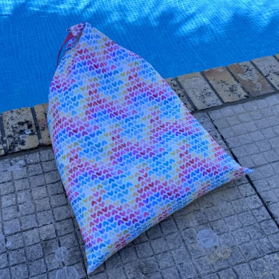 Saco de tecido com padrão colorido de corações junto a piscina