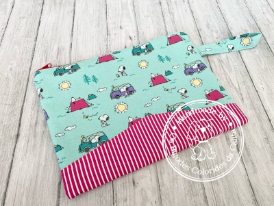 Necessaire de tecido azul claro com padrão de carrinhas e Snoopy, riscas vermelhas e brancas, sobre fundo de madeira clara