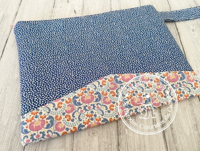 Mala de tecidos azul com pontos brancos e faixa floral colorida