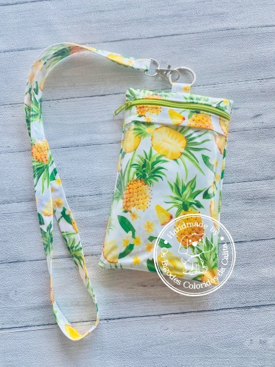 Bolsa pequena com padrão de abacaxis amarelos e folhas verdes com alça longa estampada.