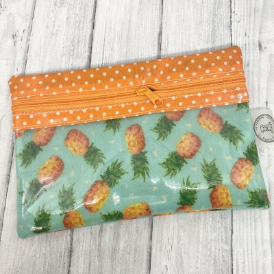 Estojo pequeno azul com ananases e topo laranja com pontos brancos