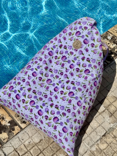 Saco de tecido com padrão de ameixas roxas junto a piscina