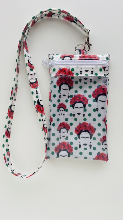 Bolsa branca com padrão de faces femininas e flores vermelhas, pontos verdes, alça longa removível.