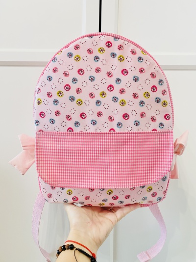 Mochila pequena rosa com padrões coloridos e bolso xadrez