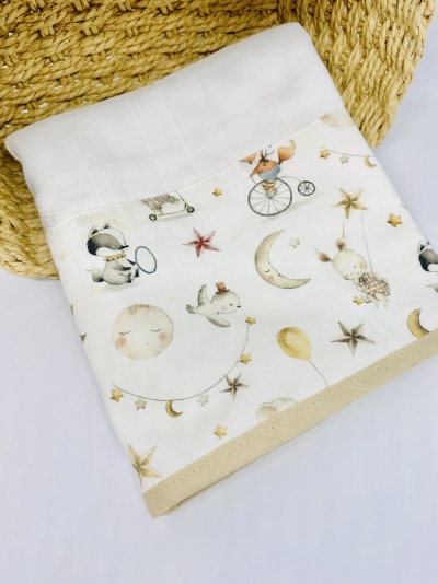 Toalha infantil branca com padrão colorido de lua, estrelas e animais sobre superfície branca.