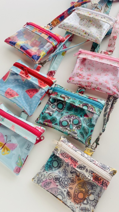 Sete bolsas pequenas transparentes com diferentes estampas e fechos coloridos