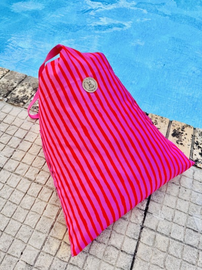 Mochila rosa com riscas vermelhas junto a piscina