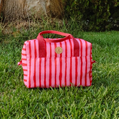 Bolsa rosa com riscas vermelhas e alças vermelhas na relva