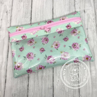 Estojo floral transparente com fecho rosa sobre madeira clara