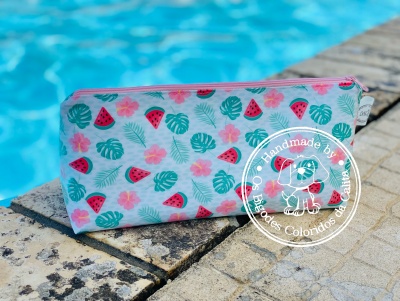Estojo de tecido colorido com padrão de melancias, folhas e flores perto de piscina