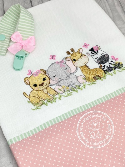 Toalha branca com bordado de animais bebés e faixa rosa às bolinhas com presilha verde e laço cor-de-rosa