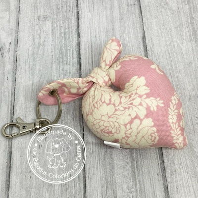 Porta-chaves em tecido rosa e bege com padrão floral em forma de coração com argola metálica.