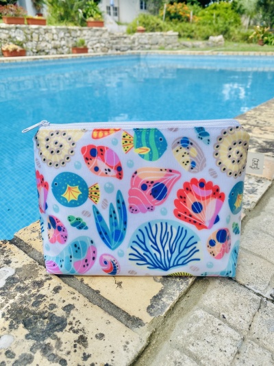Bolsa de tecido colorida com padrão de peixes e corais junto à piscina