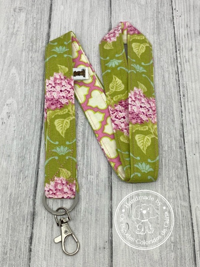 Lanyard floral tecido com fecho metálico sobre madeira cinza