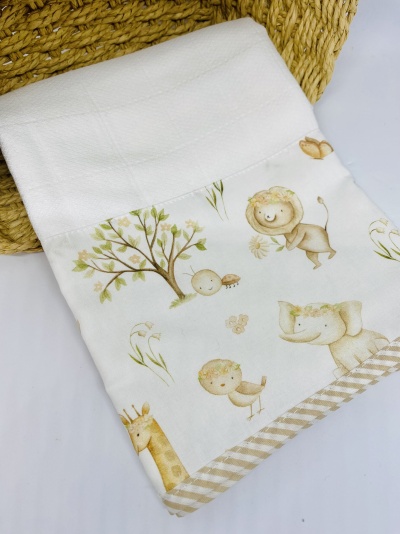 Toalha branca com estampa de animais da selva em tons pastel junto a cesto de palha