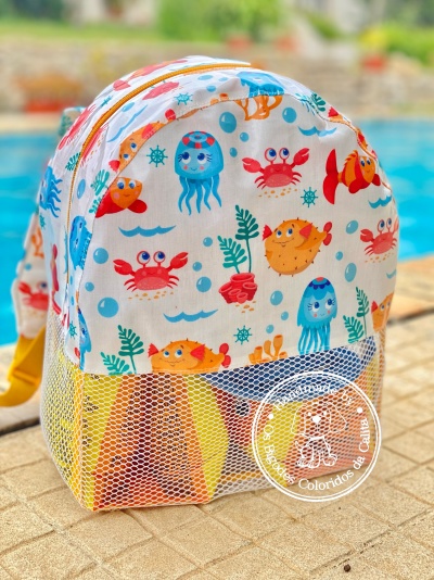 Mochila infantil com padrão de animais marinhos coloridos junto à piscina