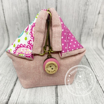 Bolsa pequena de tecido rosa com padrão floral e botão de madeira com texto handmade with love