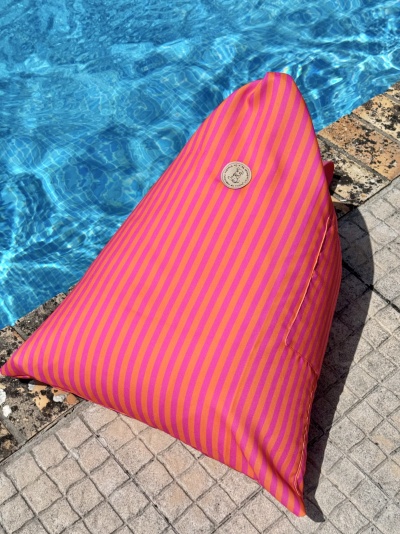 Pufe triangular riscas cor-de-rosa e laranja junto à piscina