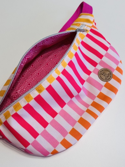 Bolsa listrada multicolorida com zíper e interior rosa em padrao geométrico