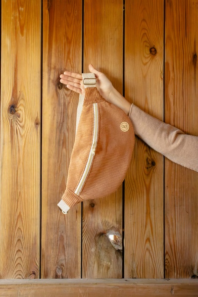 Mala de cintura castanha em veludo cotelê com fecho zip, alça branca e fundo de madeira