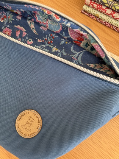 Bolsa azul com forro floral e etiqueta redonda de couro