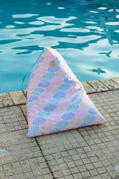 Almofada triangular com padrão de conchas coloridas junto a piscina