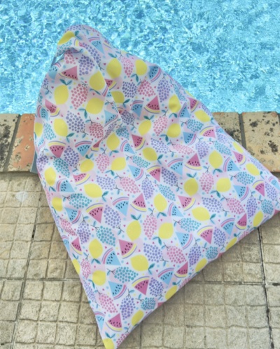Almofada colorida com padrão de frutas junto à piscina