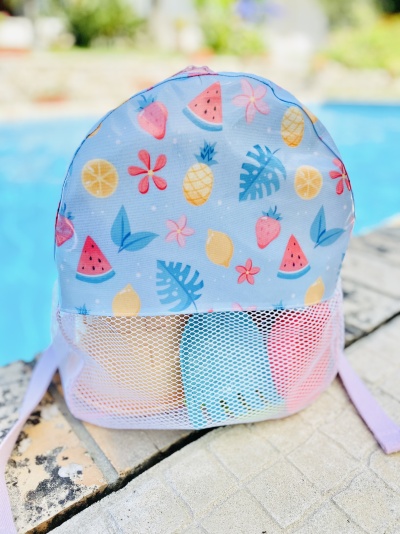 Mochila infantil azul clara com padrão de frutas coloridas e bolso frontal em rede branca.