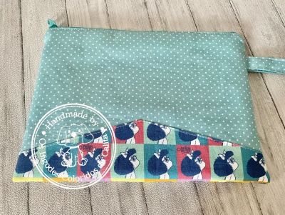 Necessaire azul com bolinhas brancas e faixa decorativa com galinhas e padrão xadrez.
